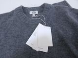 un pull gris avec une étiquette, posé sur une table blanche