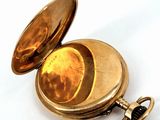 a gold pocket watch sitting on a white surface
