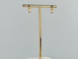une table en marbre blanc et doré sur laquelle sont posées deux boucles d’oreilles
