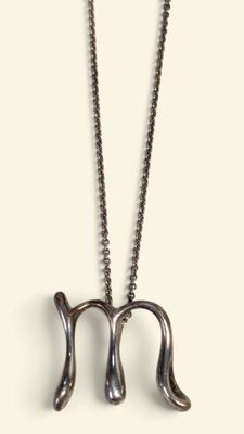 Collier représentant un signe du zodiaque, avec une chaîne en argent, sur fond blanc