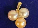 un gros plan d'un pendentif composé d'une perle jaune et de diamants, sur un fond bleu
