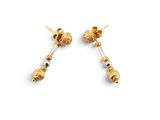 une paire de boucles d'oreilles en or ornées de perles noires sur fond blanc