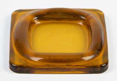 a brown square shaped glass ashtray on a white surface