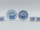 several blue and white dishes and cups are arranged on a white surface