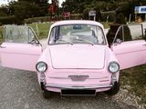 a pink car that is parked on the side of the road