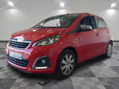 une voiture rouge est garée dans une pièce au sol en damier