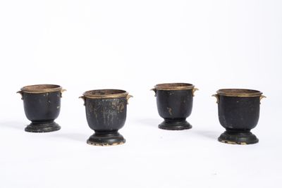 trois vases noirs munis d'anses, posés sur une surface blanche
