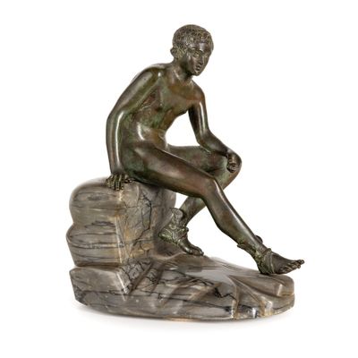 statue en bronze représentant un homme assis sur un rocher, les jambes croisées