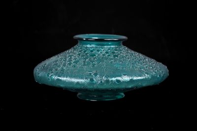 a glass vase that is sitting on a black surface