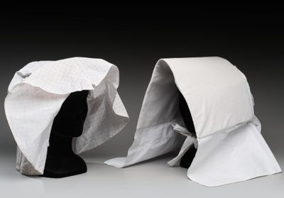 une paire de mannequins noirs dont la tête est recouverte d'un tissu blanc