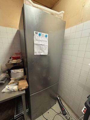 une photo d'un réfrigérateur dans une cuisine très encombrée