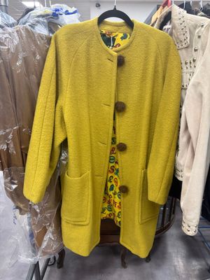 a yellow coat hanging on a rack in a clothing store
