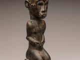 a small statue of a man sitting on top of a wooden block