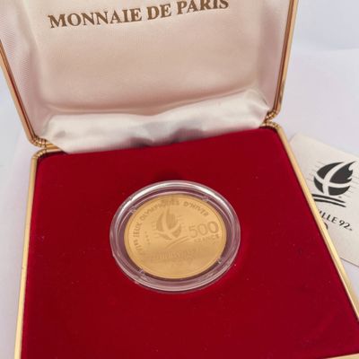 l'image d'une pièce d'or dans un écrin rouge posé sur un fond blanc