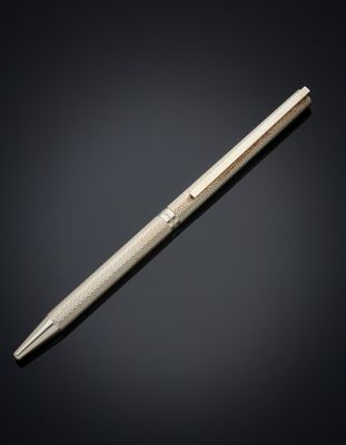 a silver ballpoint pen sitting on top of a black surface