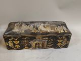 an old black and gold box sitting on top of a white table