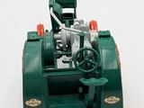 a green machine with a red handle on a white surface