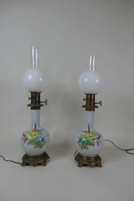 une paire de lampes en verre blanc ornées de motifs floraux, posées sur une table