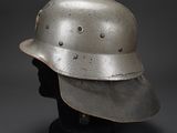 a silver helmet on a black mannequin head on a gray background