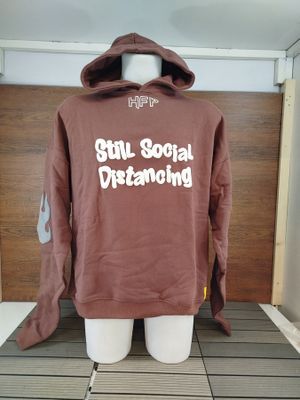a mannequin wearing a brown hoodie with the words still social distancing printed on it