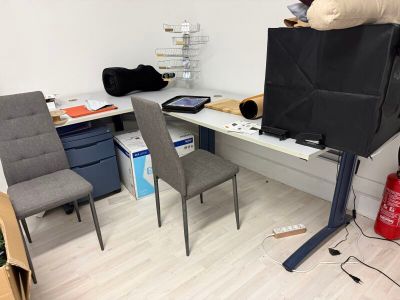 a desk with two chairs and a television in the corner