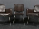 trois fauteuils en cuir marron placés les uns à côté des autres contre un mur gris