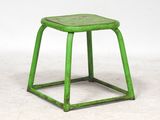 un vieux tabouret vert posé sur un sol blanc