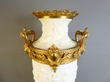un vase blanc et doré, bordé d'or, posé sur une table