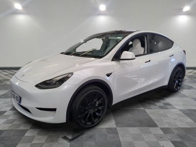 un SUV Tesla blanc garé sur un sol à damier dans un garage