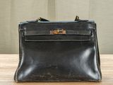 an old black purse sitting on top of a wooden table