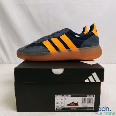Les baskets adidas sont posées sur une boîte, sur une surface blanche.