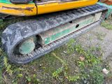 a yellow and black excavator sitting in the grass