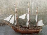 une maquette en bois d'un voilier posée par terre