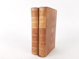 two old books sitting on top of each other on a white surface