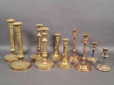 many different types of brass candlesticks on a table