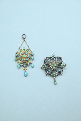 two small pendants with turquoise and green beads on a white surface