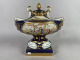 a blue and white vase with a gold decoration on it