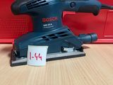 La ponceuse orbitale Bosch est posée sur une table, à côté d'une boîte rouge.