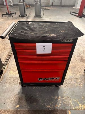 La boîte à outils rouge est posée par terre dans le garage.