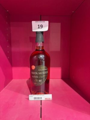 une bouteille d'alcool vide posée sur une étagère rose, dans une boîte rose