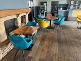 brightly colored chairs and tables sit in front of a fireplace in a restaurant