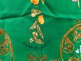 a close up of a green table cloth with yellow and purple flowers on it