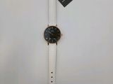 a white watch with a black face on a white strap