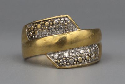 une image représentant une bague en or sertie de diamants posée sur une surface grise