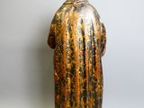 une vieille statue représentant un homme coiffé d'un chapeau et vêtu d'une robe
