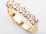 Gros plan sur une bague en or sertie de cinq diamants, sur fond blanc