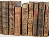 several old books are lined up on a shelf in a row