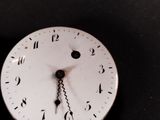 a white clock with roman numerals on it ' s face