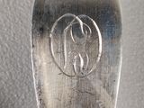 a spoon with a monogram on it sitting on a table