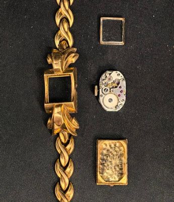 une montre en or avec une chaîne, posée sur un fond noir